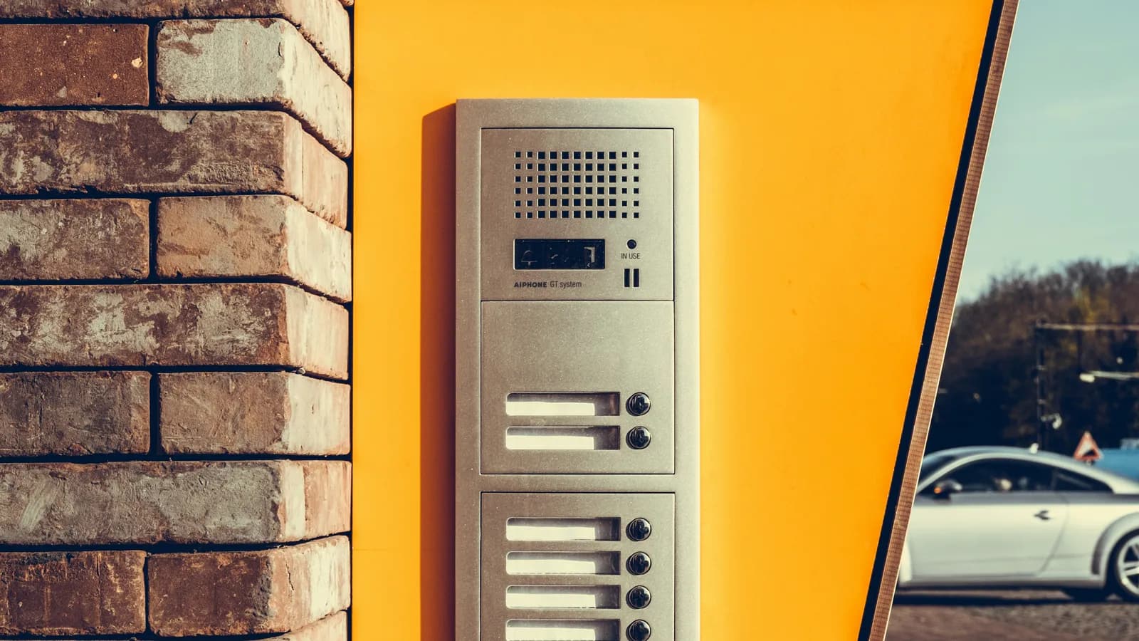 Interphone d'immeuble sur un mur jaune