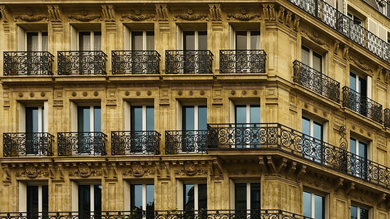 Façade haussmannienne en pierre de taille et balcons en fer forgé à Paris, au soleil