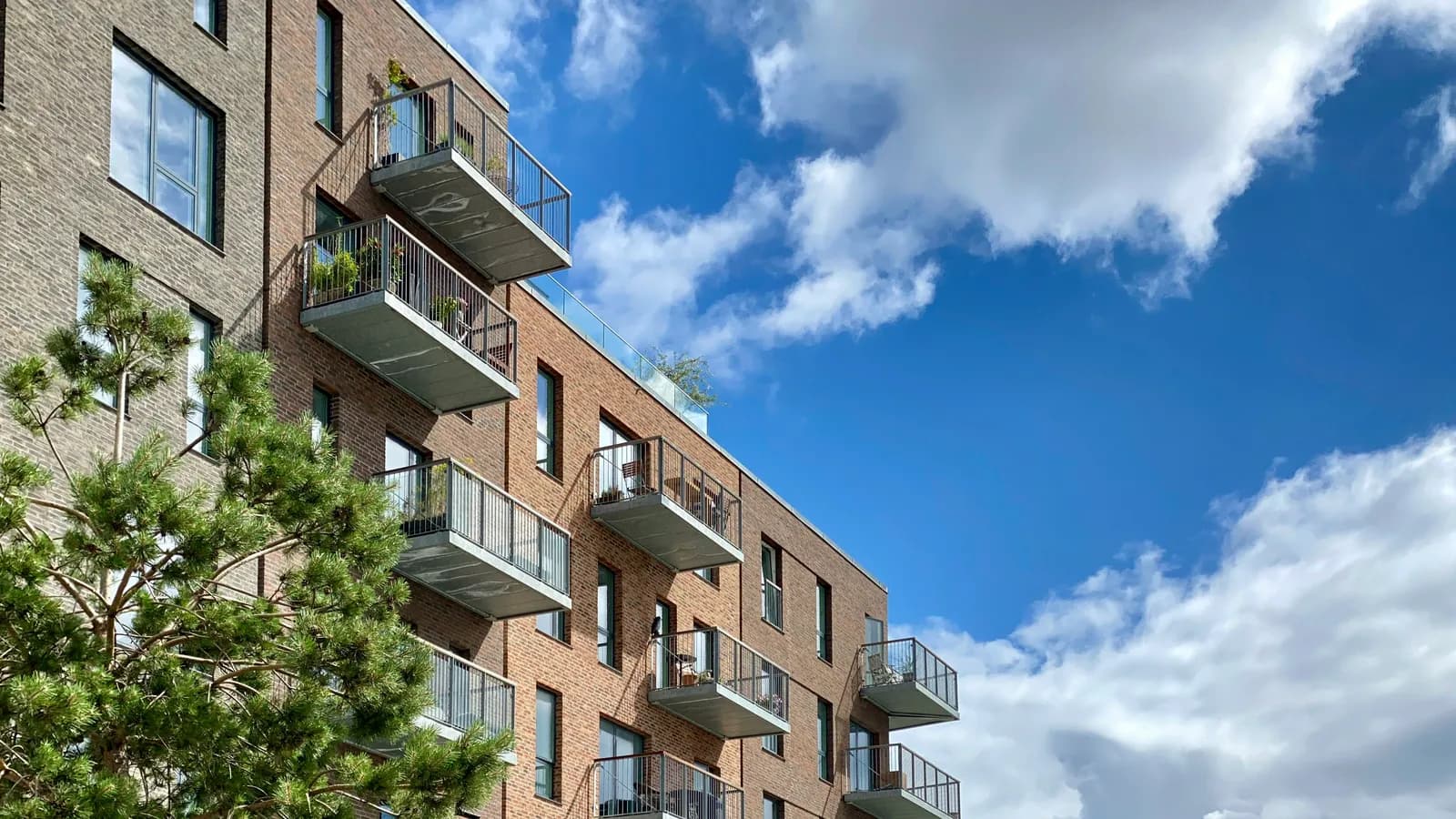 Immeuble d'habitation récent en brique avec balcons sous un ciel bleu